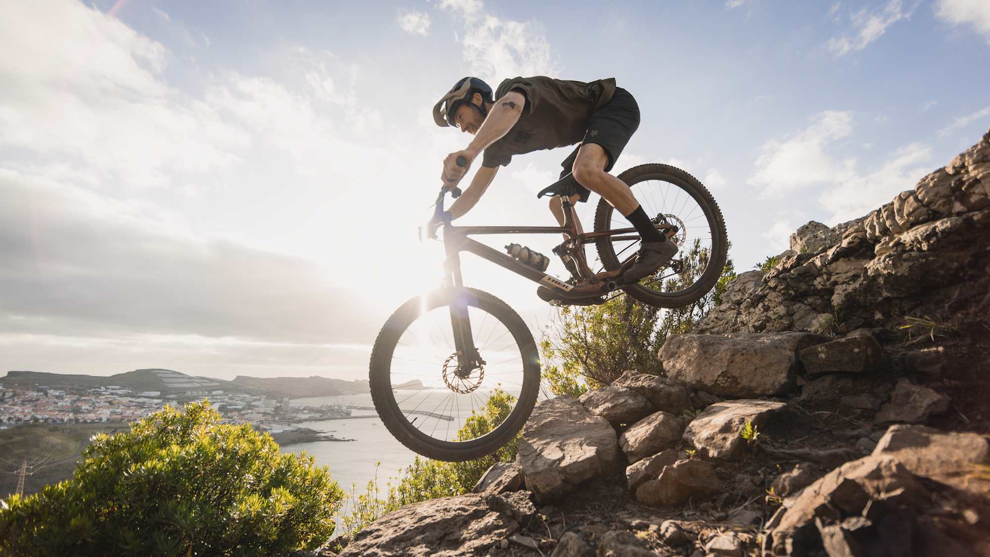 Mountainbiker springt eine Felskante auf einem Trek Top Fuel an der Küste