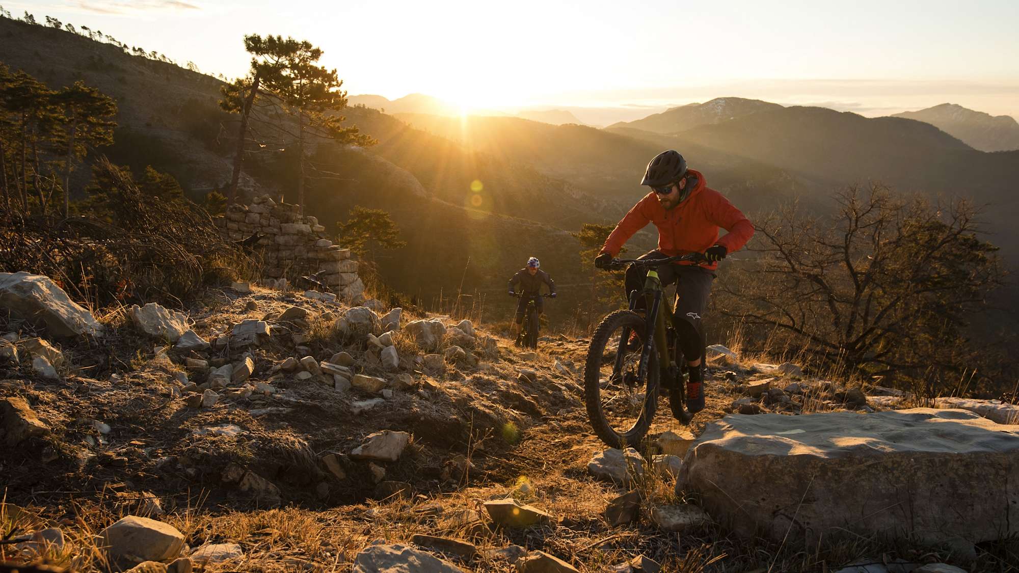 Zwei E-Mountainbiker auf einem Bergkamm im Sonnenuntergang mit Trek Powerfly