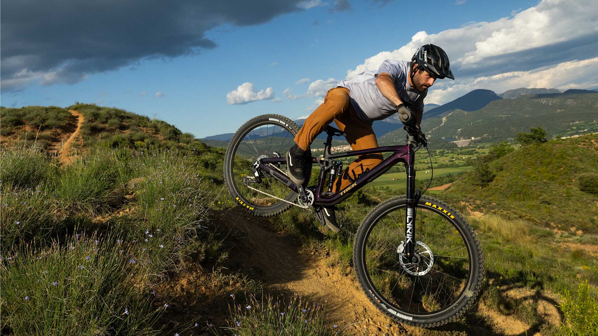 Mountainbiker carvt einen Trail auf einem Trek Fuel EX vor Bergpanorama