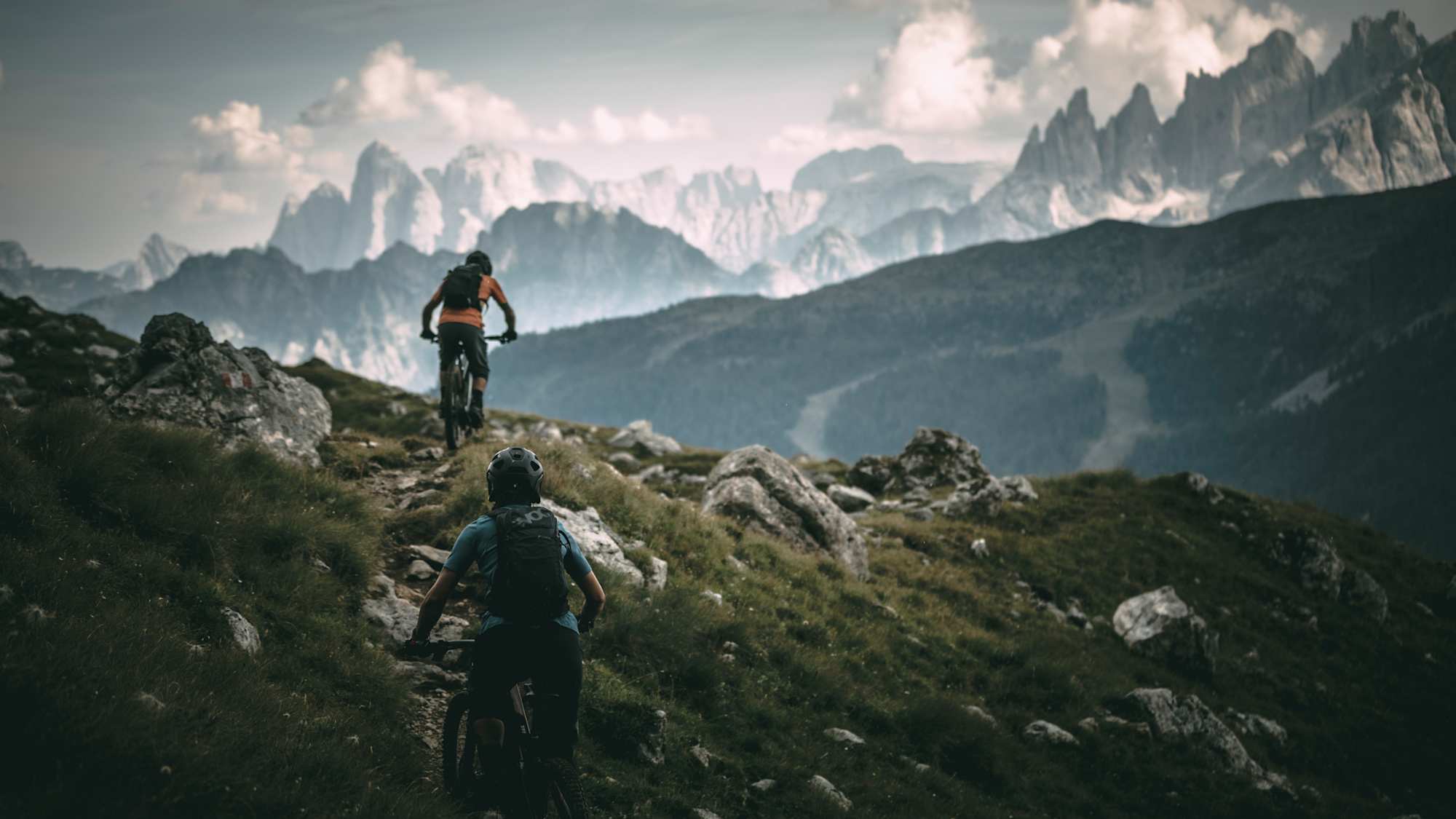 Zwei E-Mountainbiker auf einem Alpentrail vor den Dolomiten mit Trek Rail